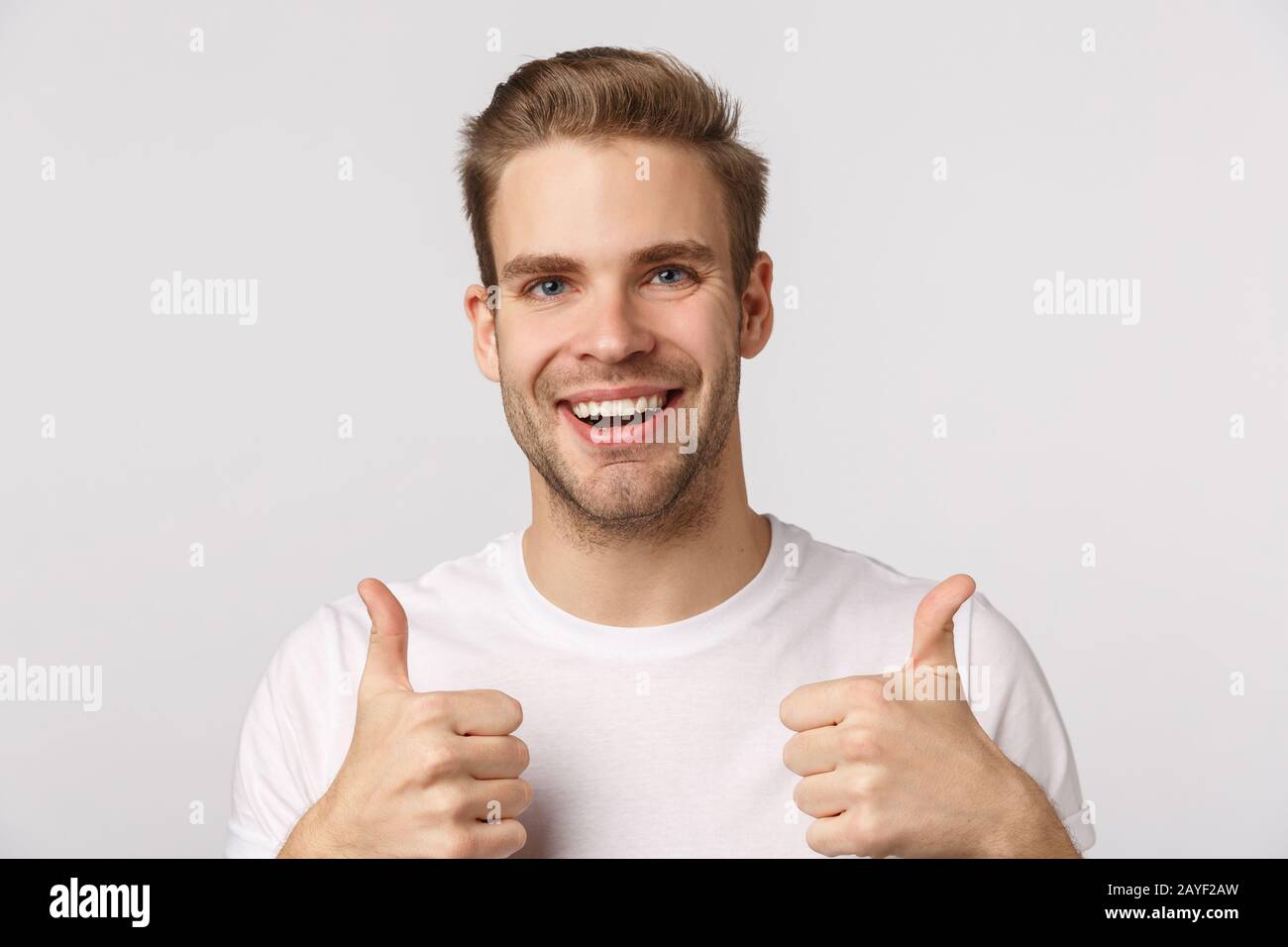Nahaufnahme Studio positiv, zufrieden blonde blonde kaukasische Kerl zeigen Daumen-oben und lächeln, ermutigen Sie Freunde, große Wahl zu treffen, rec Stockfoto