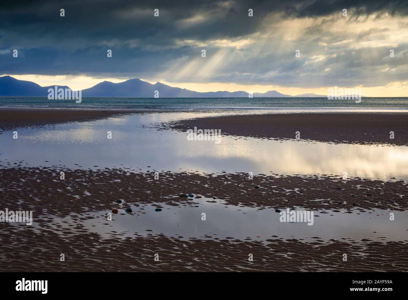 Lichtschächte über der Halbinsel Llŷn, die vom Strand Llanddwyn auf der Insel Anglesey eingenommen wurden. Stockfoto