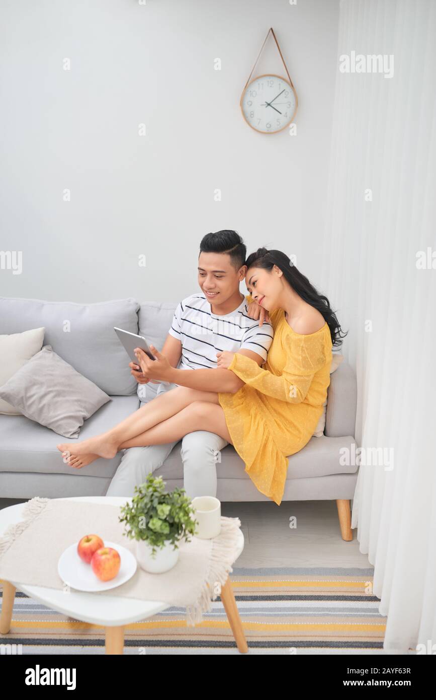 Junges Paar erholsamen luxuriösen Zuhause mit Tablet-PCs lesen im Wohnzimmer auf dem Sofa couch. Stockfoto