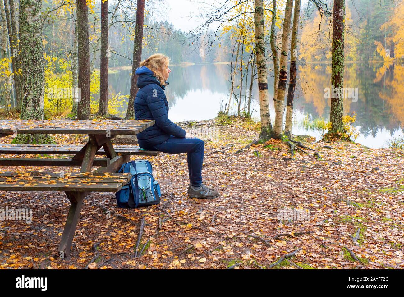Frau sitzt am Picknicktisch in finnischer Natur Stockfoto