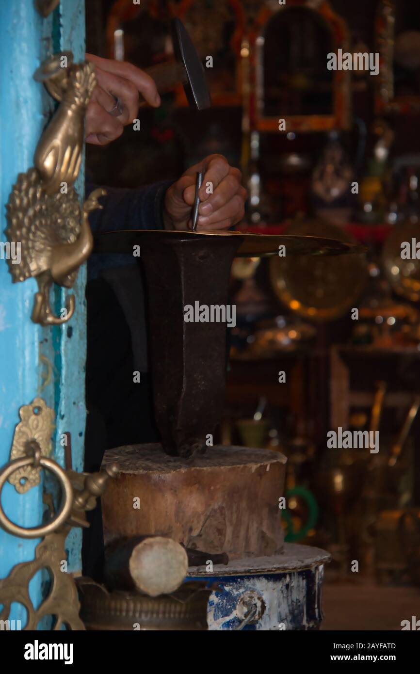 Handwerkerwerkstatt, in der ein Mann das Metall meißelt Stockfoto