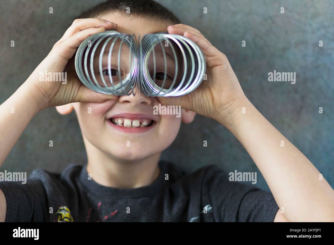 Ein Junge schaut durch ein slinkiges Spielzeug. Stockfoto