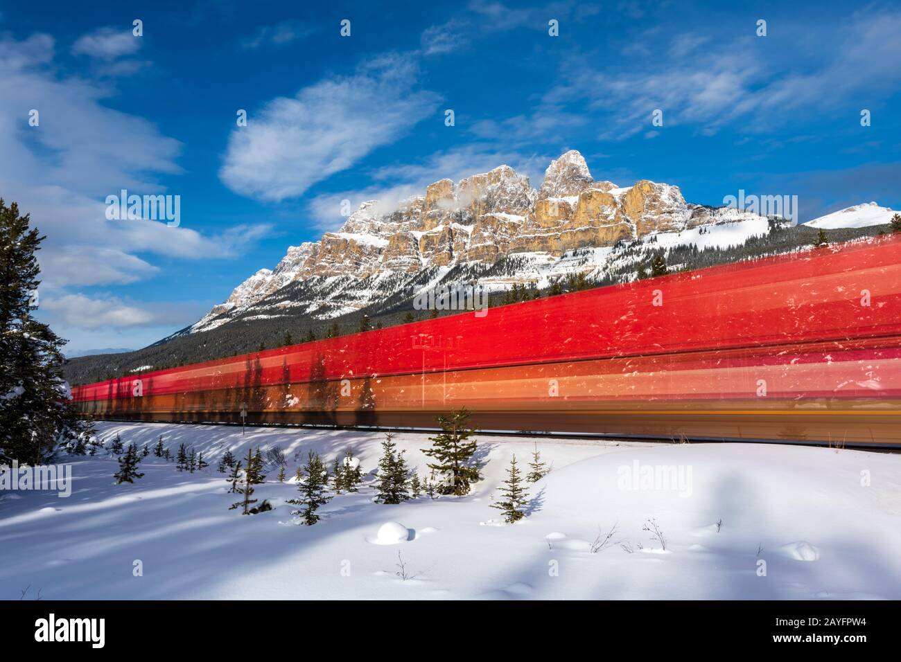 Lange Exposition der roten Lok, die im Winter am Castle Mountain in der Nähe von Banff, Alberta, Kanada vorbeiführt Stockfoto