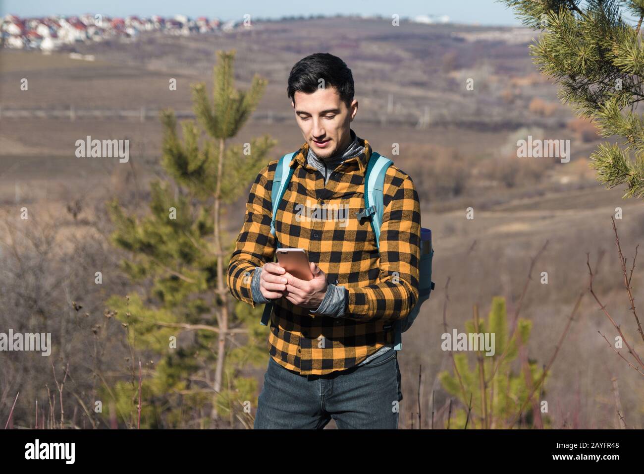 Draußen im Frühling. Gutaussehender Mann auf dem Land mit dem Telefon zum Navigieren Stockfoto