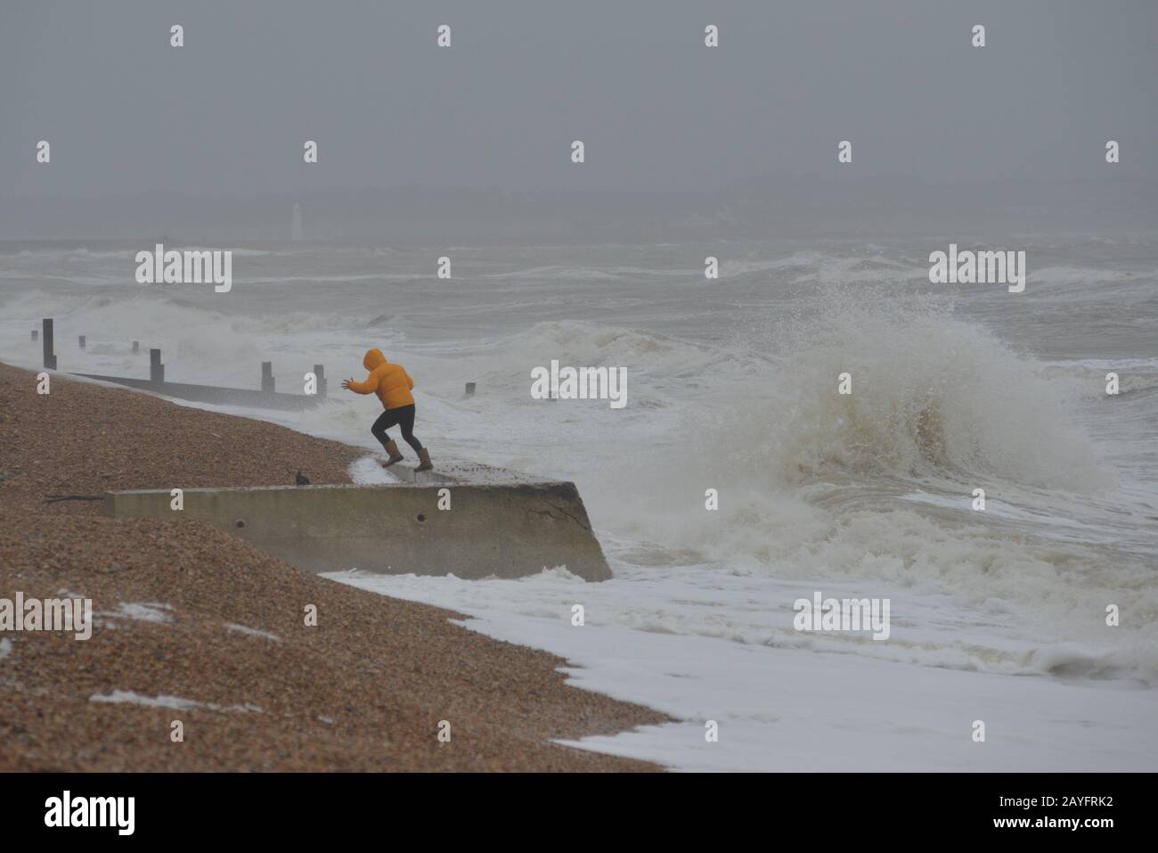 Sturm Dennis, klassifiziert als Bombensturm, bringt Sturmwind und heftigen Regen an die Südküste. Der starke Wind peitscht das Meer in riesige Wellen. Ein Mann am Strand kommt einer großen Welle nahe, Milford-on-Sea, Hampshire, England, Großbritannien, 15. Februar 2020, Wetter: Stockfoto