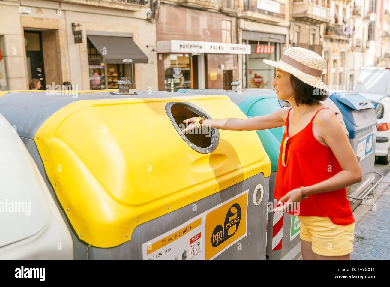 17. JULI 2018, TARRAGONA, SPANIEN: Frau wirft Papier in einen Papierkorb auf einer Straße in der Stadt Stockfoto