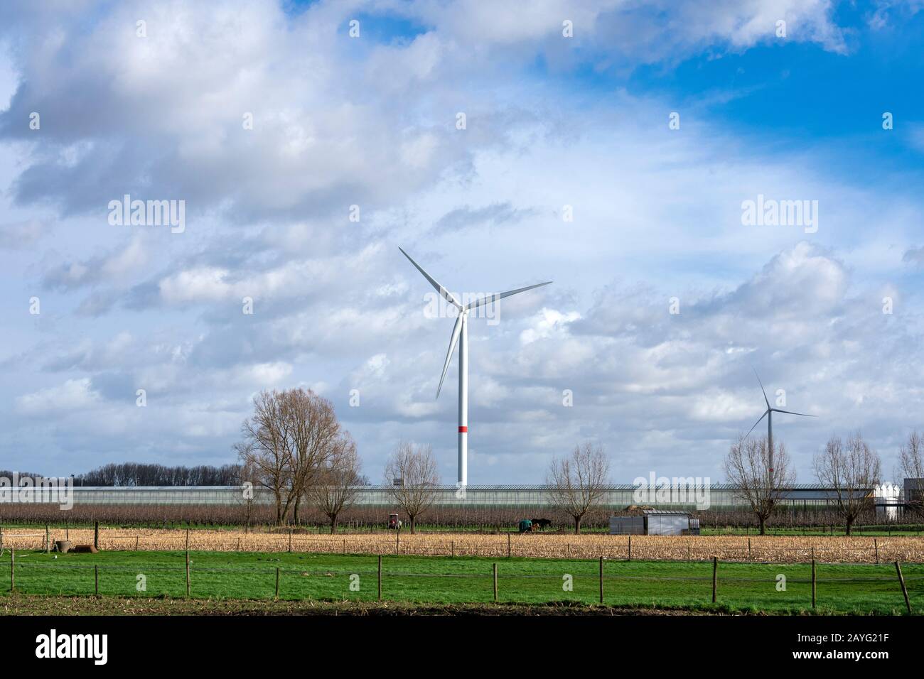 Windmühlen an einem großen grünen Haus an einem bewölkten Tag, an dem die Sonne durchbricht Stockfoto