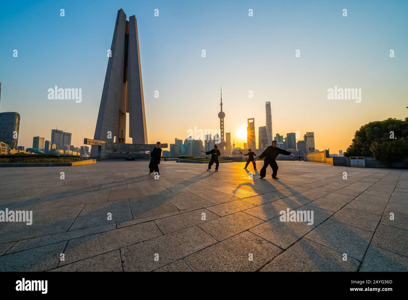 Shanghai, China - 6. Februar 2018: Menschen, die Tai Chi am Bund bei Sonnenaufgang spielen, Oriental Pearl Tower und andere berühmte Wolkenkratzer im Hintergrund, in Stockfoto