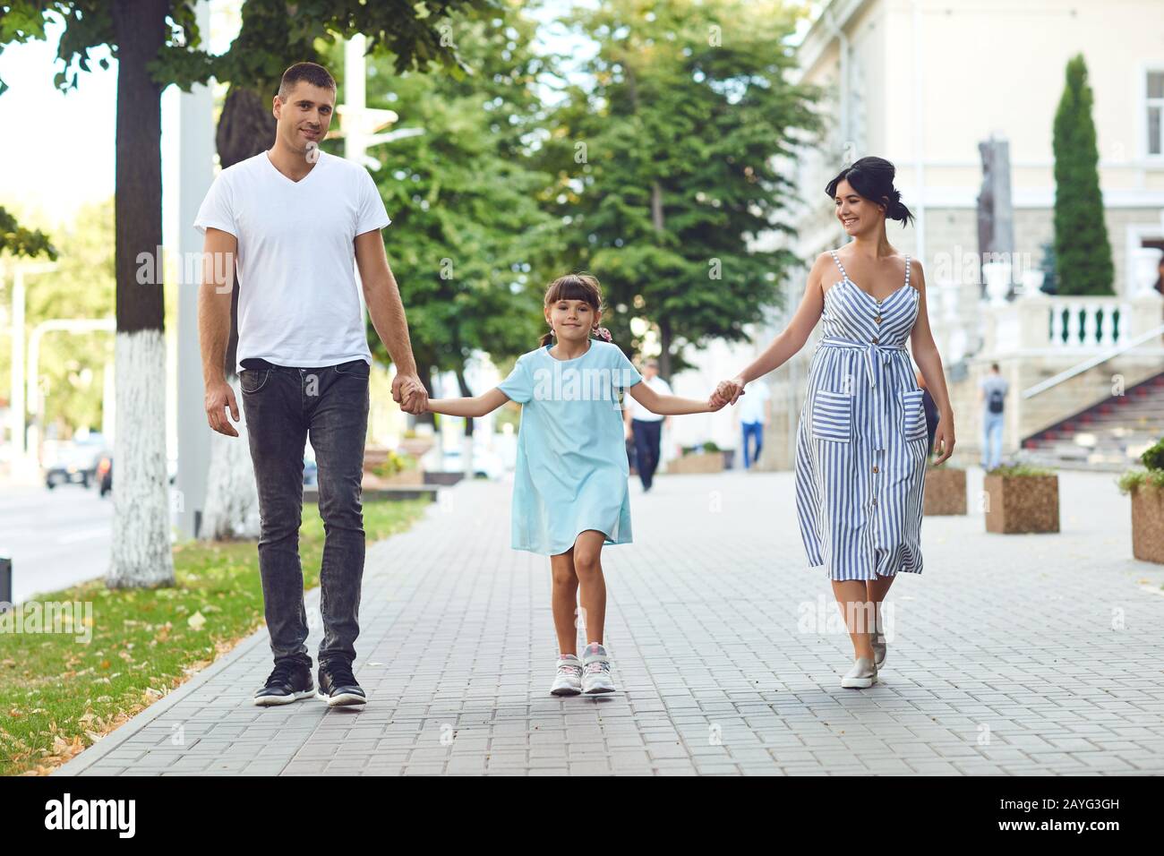 Fröhliche Familie, die in der Straße der Stadt zusammen spazieren geht Stockfoto