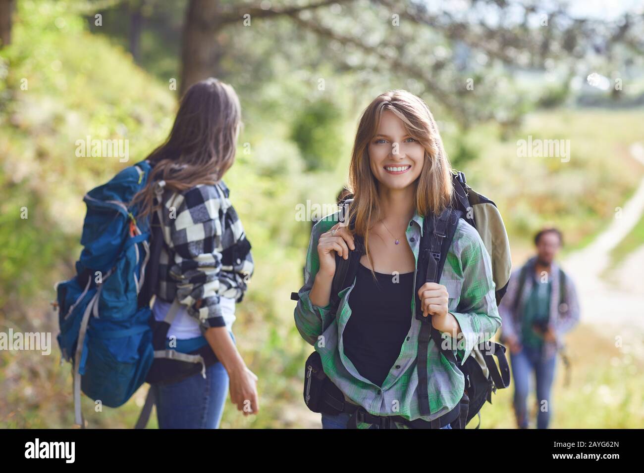 Mädchen mit Rucksack mit Freunden, Touristen, die in der Natur spazieren. Stockfoto