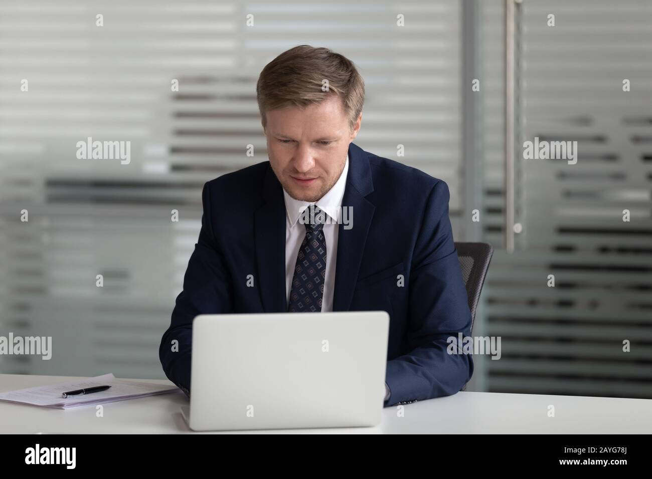 Konzentrierter CEO von Männern beschäftigt sich mit der Verwendung von Laptops am Arbeitsplatz Stockfoto
