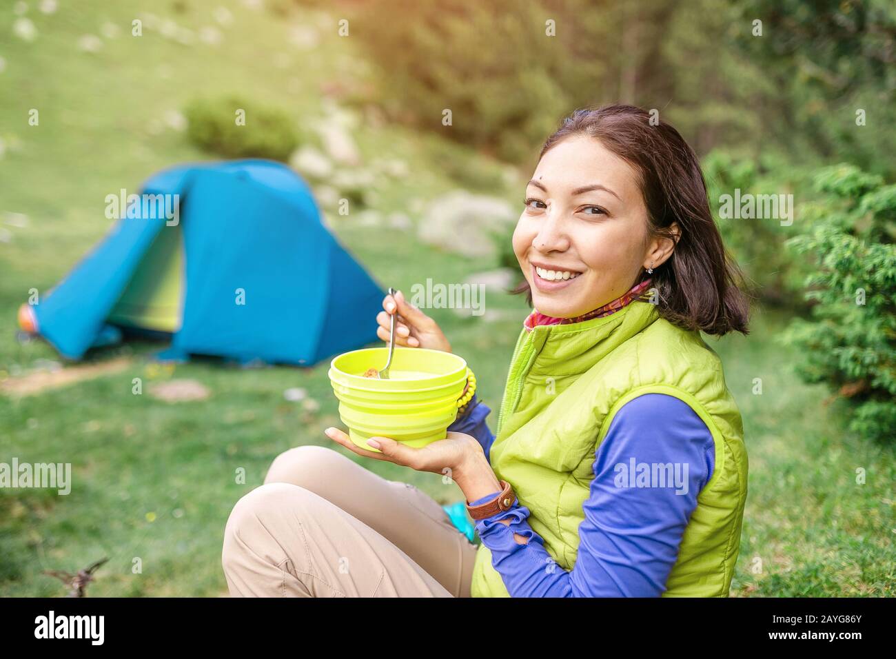 Morgens warmes Frühstück im Wald - Frau Wanderer, die beim Zelten in den  Bergen warmes Essen in der Nähe des Zeltes isst Stockfotografie - Alamy