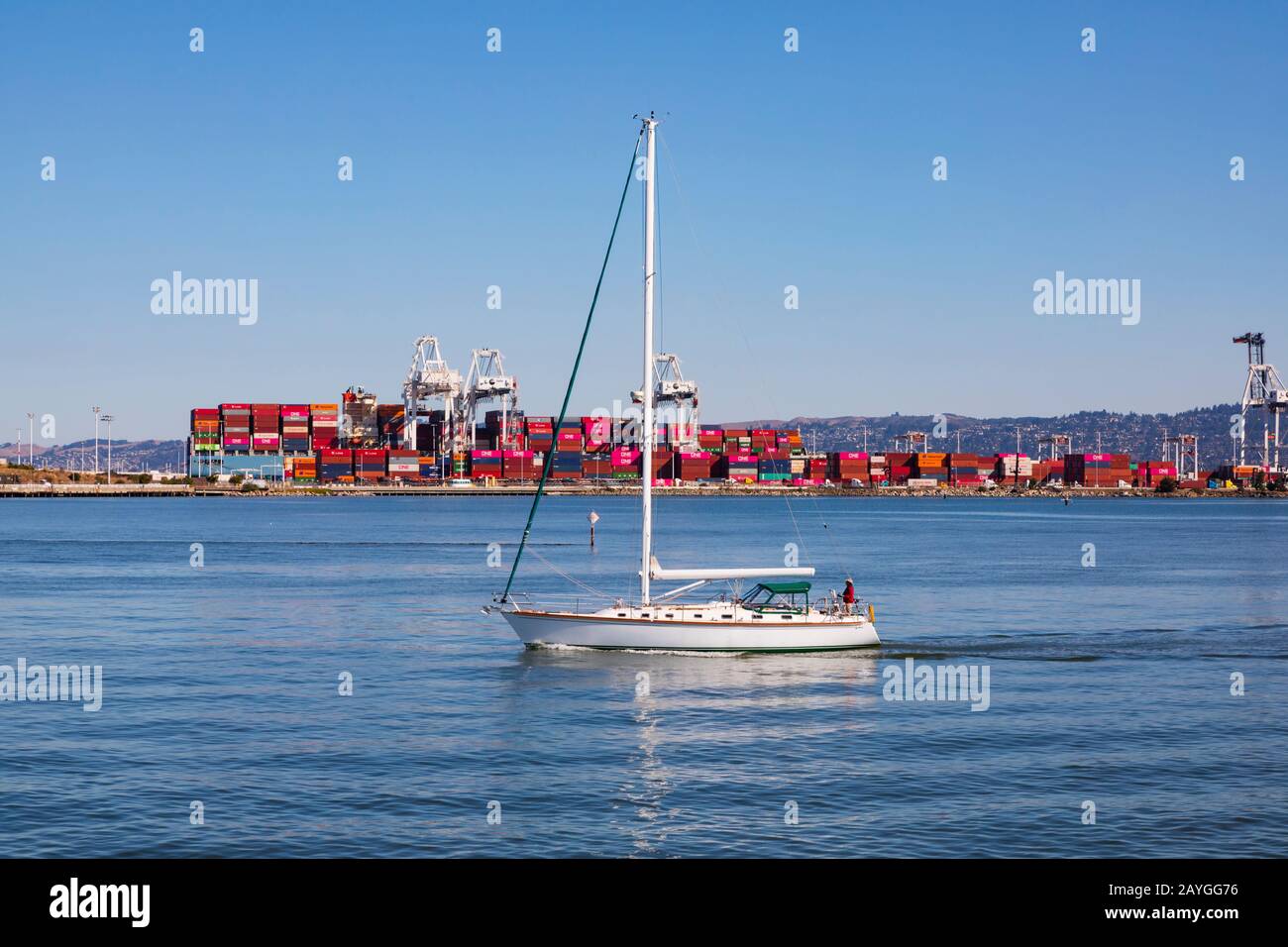 Eine Yacht führt am Containerterminal Port of Oakland vorbei und führt in die San Francisco Bay. Kalifornien, USA Stockfoto