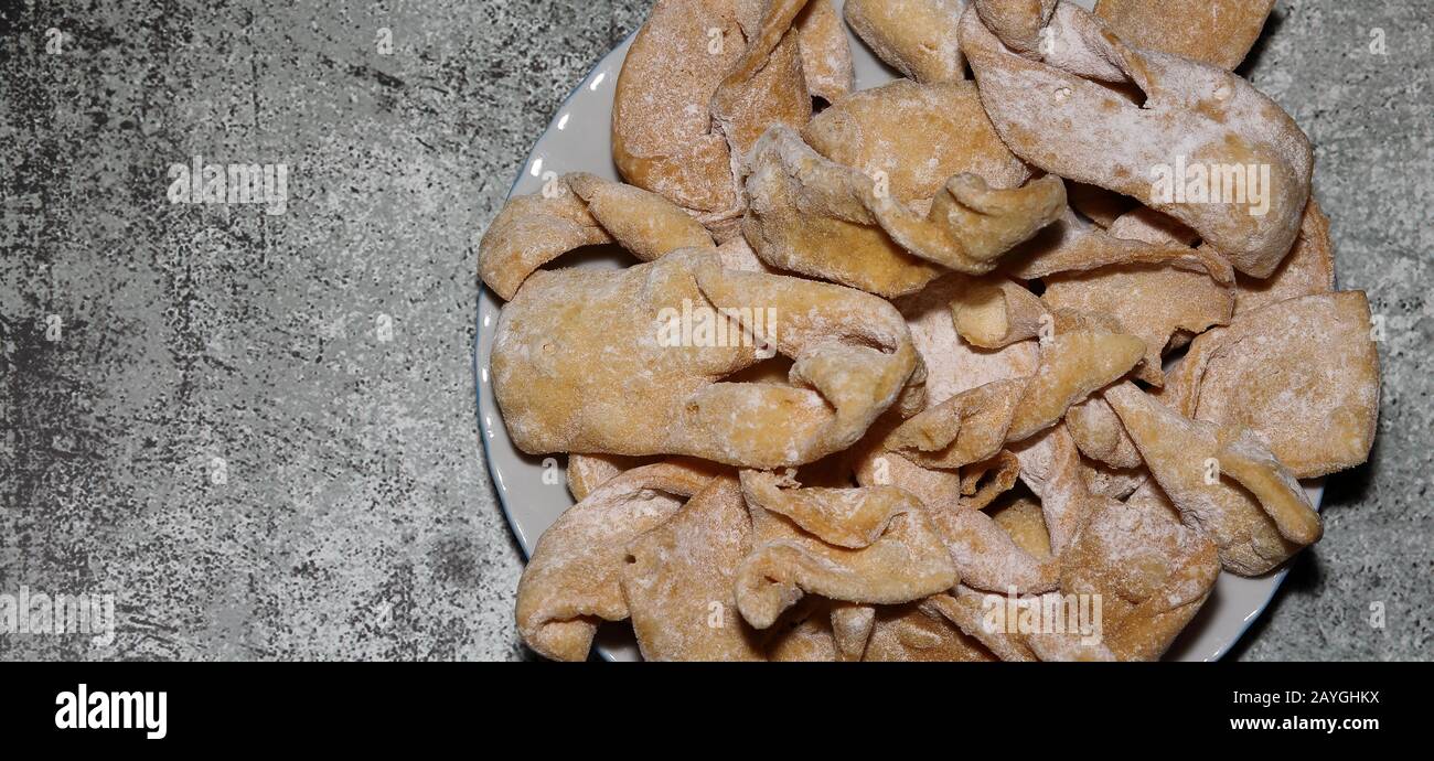 Süßigkeiten / Wüste / Kuchen namens faworki / Chrost auf Polnisch serviert traditionell am Donnerstag Fett, Teller auf steinigen Tisch, flach lag dicht oben. Stockfoto