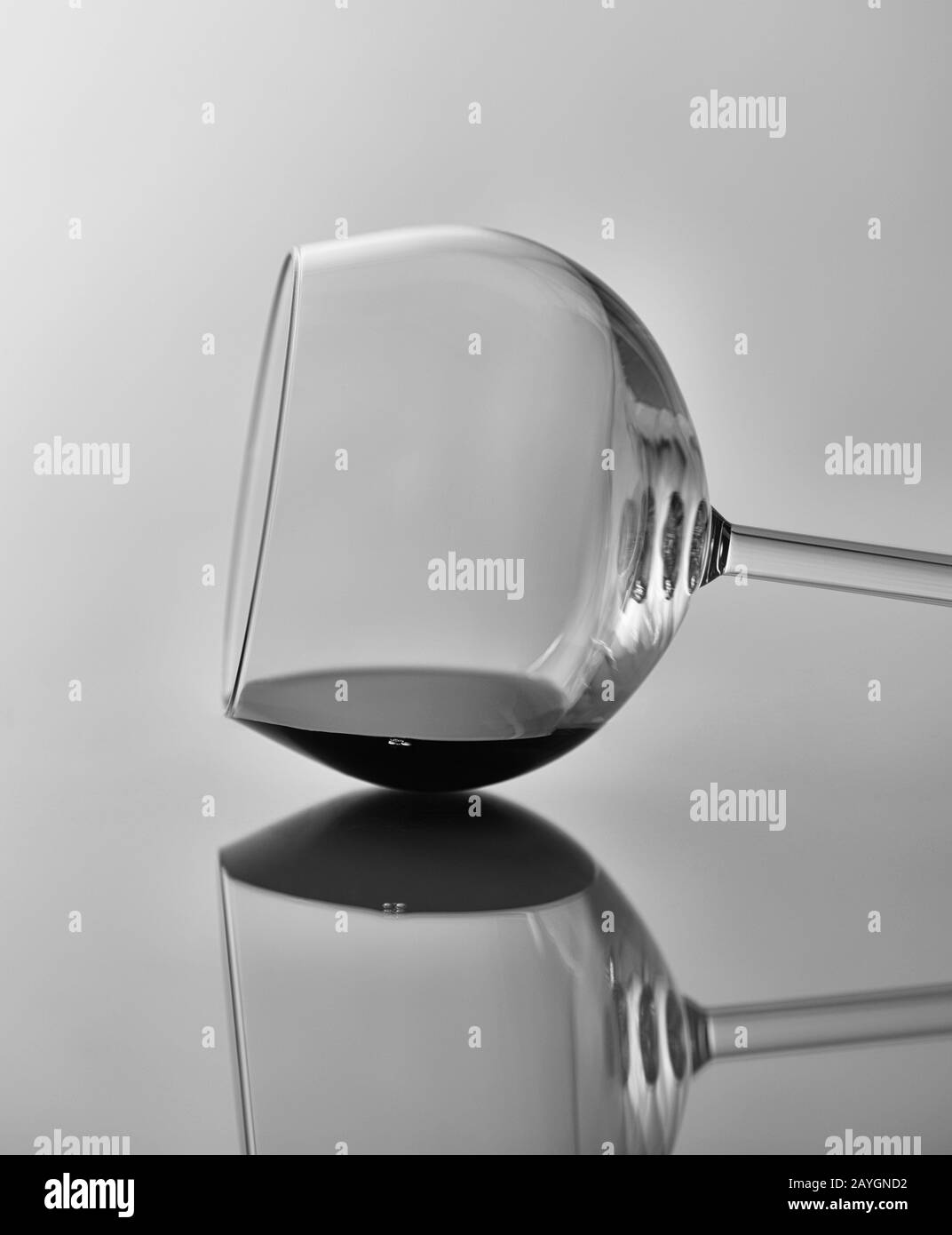Weinglas-Stillleben: Schwarz-Weiß-Bild eines Weinglases an seiner Seite mit Spiegelung. Stockfoto