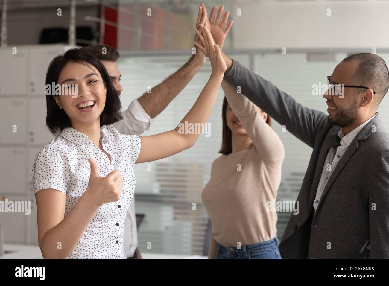 Fröhliche weibliche Angestellte zeigen Daumen hoch am Teambuilding Stockfoto