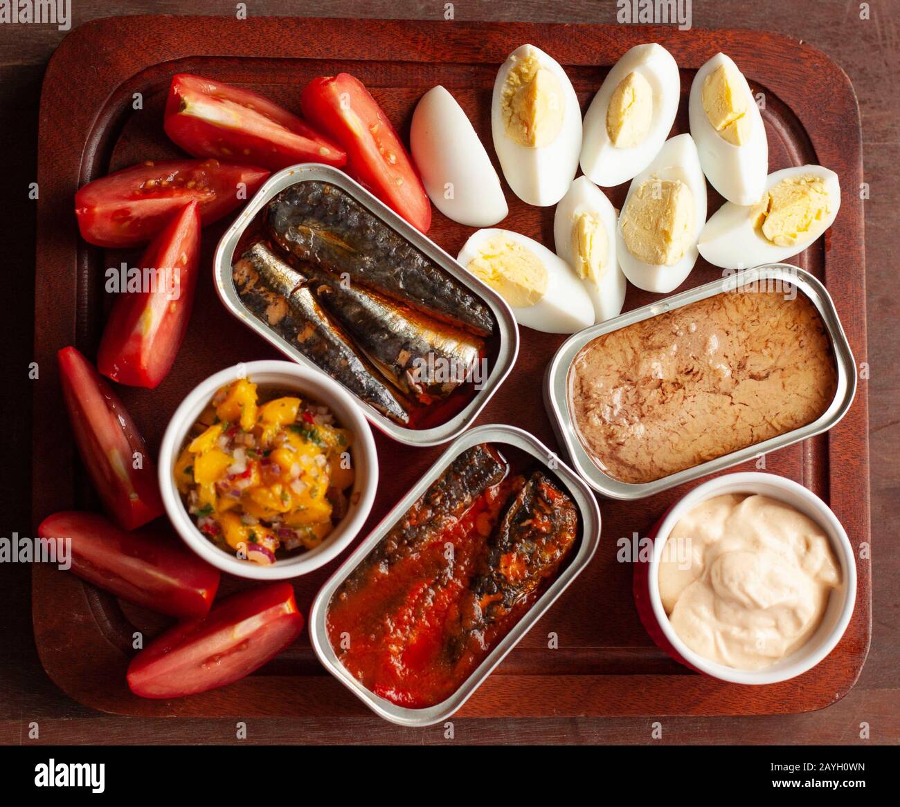 Festliche Platte mit Konserven, Thunfisch, Tomaten, gekochten Eiern, Chutney und Sauce Stockfoto