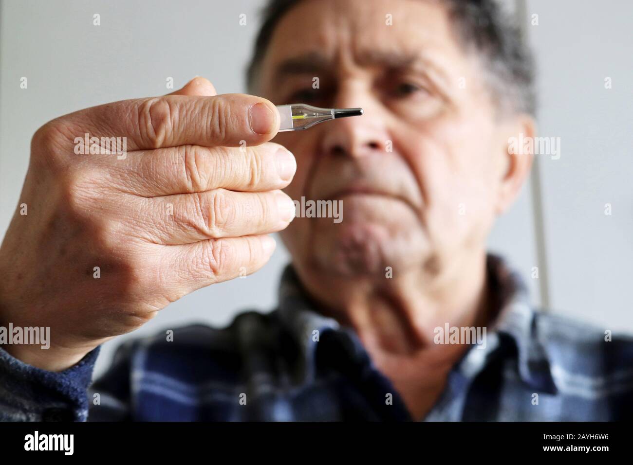 Älterer Mann misst die Körpertemperatur mit einem Quecksilberthermometer. Konzept von Fieber, Kaltbehandlung, Symptome von Coronavirus Stockfoto