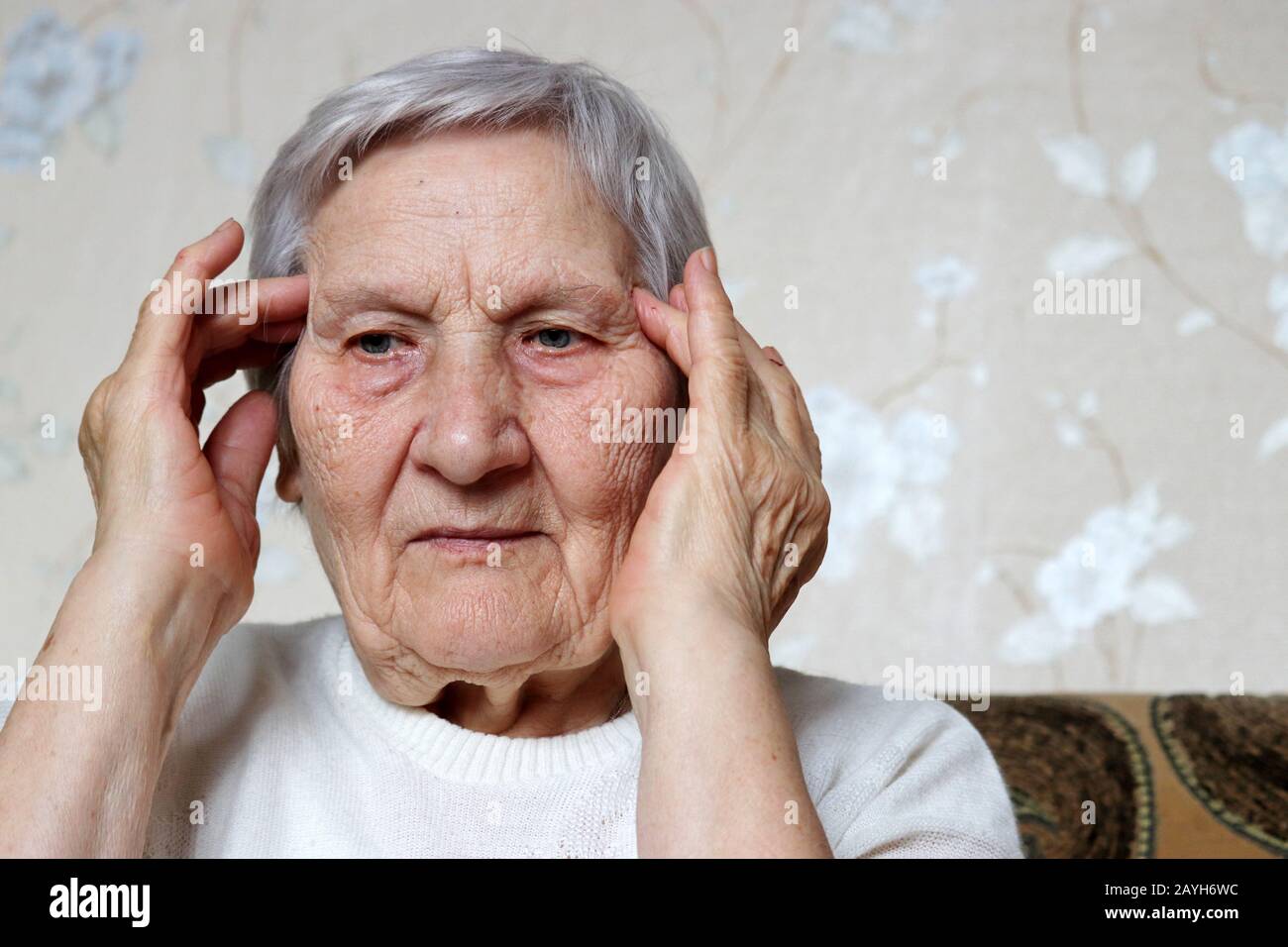 Ältere Frauen massieren die Tempel mit ihren Händen. Weibchen mit grauem Haar, Kopfschmerzen, Gesundheit und Alter Stockfoto