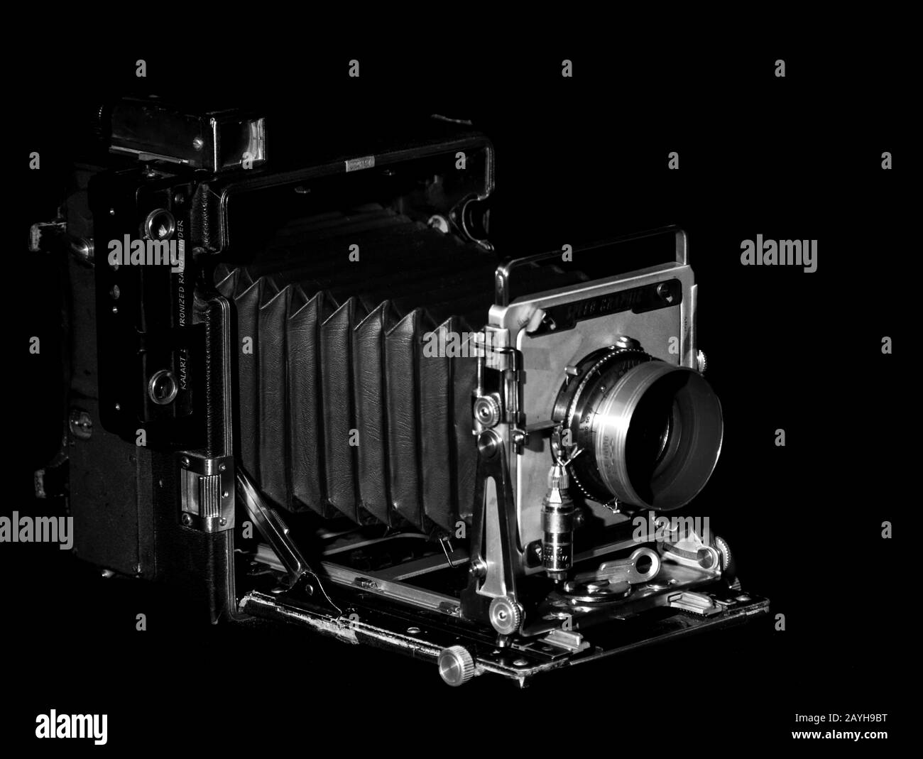 Vintage Speed Graphic Mittelformatfilmkamera auf schwarzem Hintergrund. Seitenansicht, Low-Key-Beleuchtung, Schwarz-Weiß-Foto. Stockfoto