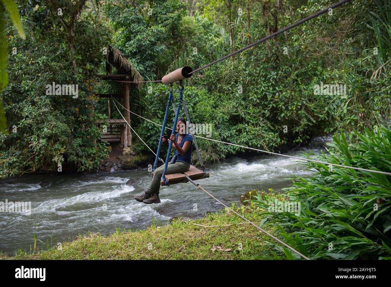 Menschen, die den Fluss Mindo mit einer Seilbahn zur El Monte Sustainable Lodge in den Nebelwäldern von Mindo, in der Nähe von Quito, Ecuador, überqueren. Stockfoto