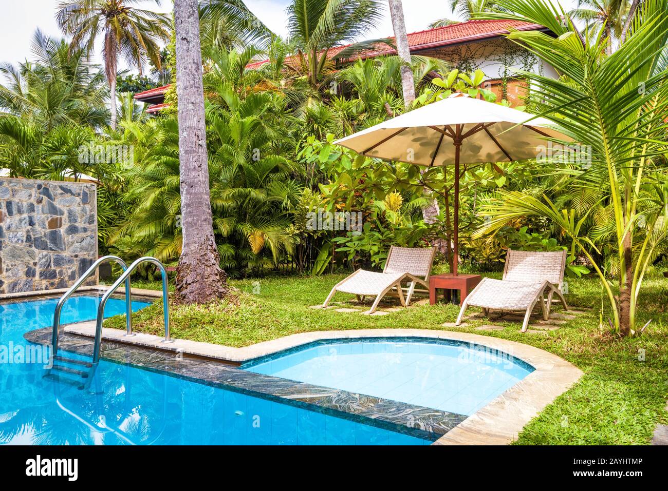 Sri Lanka - 31. Oktober 2017: Pool mit Sonnenschirm und Strandbetten in einem tropischen Hotel oder Haus. Wunderschönes Schwimmbad im Hinterhof. Pool mit blauer Klee Stockfoto