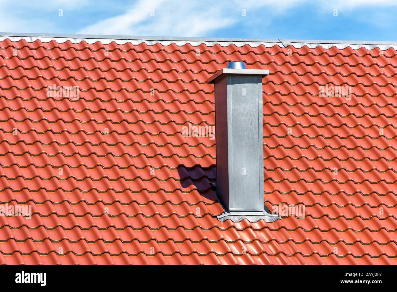 Kamin auf sauberem Dach des Wohnhauses. Metallschornsteinrohr auf dem Hintergrund roter Fliesen. Modernes Belüftungssystem auf dem Dach. Kamin aus Stahl geschlossen Stockfoto