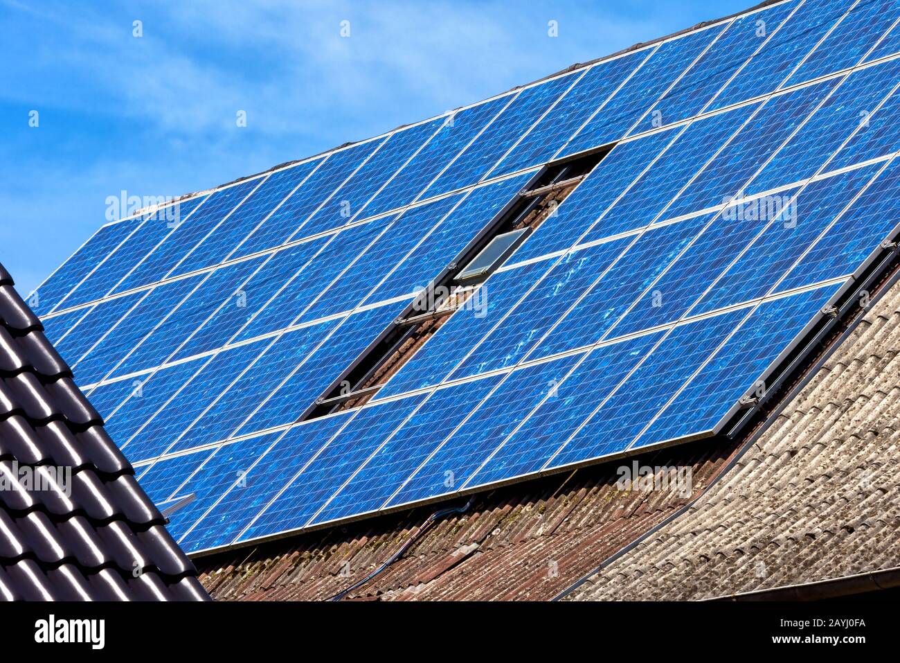 Solarpanel auf dem Dach des Wohnhauses. Sonnensystem auf dem Dach der Nahaufnahme. Blaue Solarzellen auf der Gebäudeoberseite für alternative Energie. Fotovoltaik Stockfoto