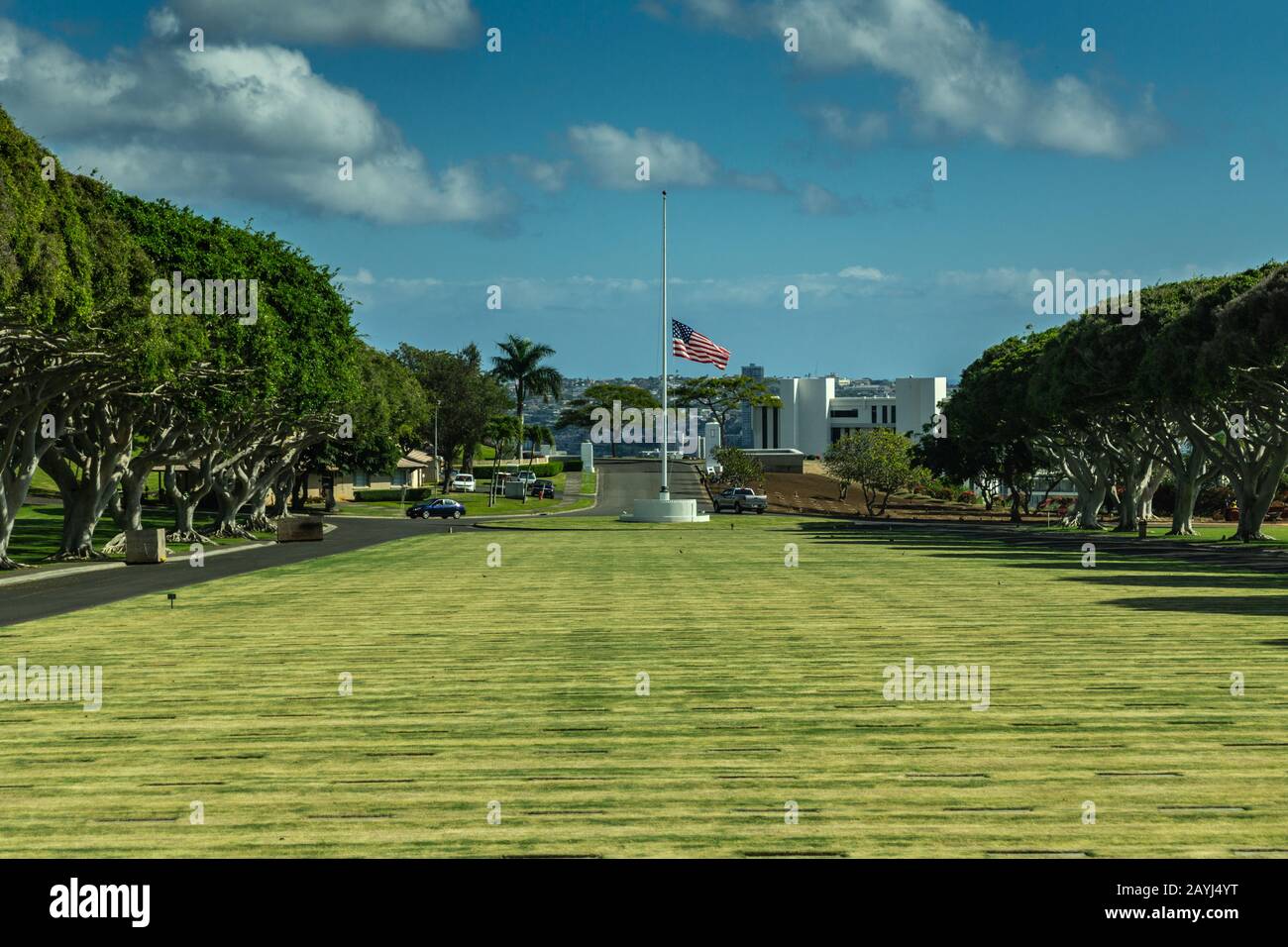 Oahu, Hawaii, USA. - 10. Januar 2012: Weitschuss über dem grünen National Memorial Cemetery of the Pacific mit Flaggenhalbmast unter blauer Wolkenlandschaft. Grün Stockfoto