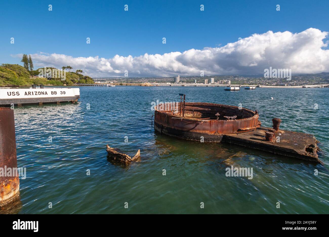 Oahu, Hawaii, USA. - 10. Januar 2012: Pearl Harbor. Rostige Teile der USS Arizona sticht aus grünlichem Meerwasser mit der Skyline von Honolulu zurück unter B. Stockfoto