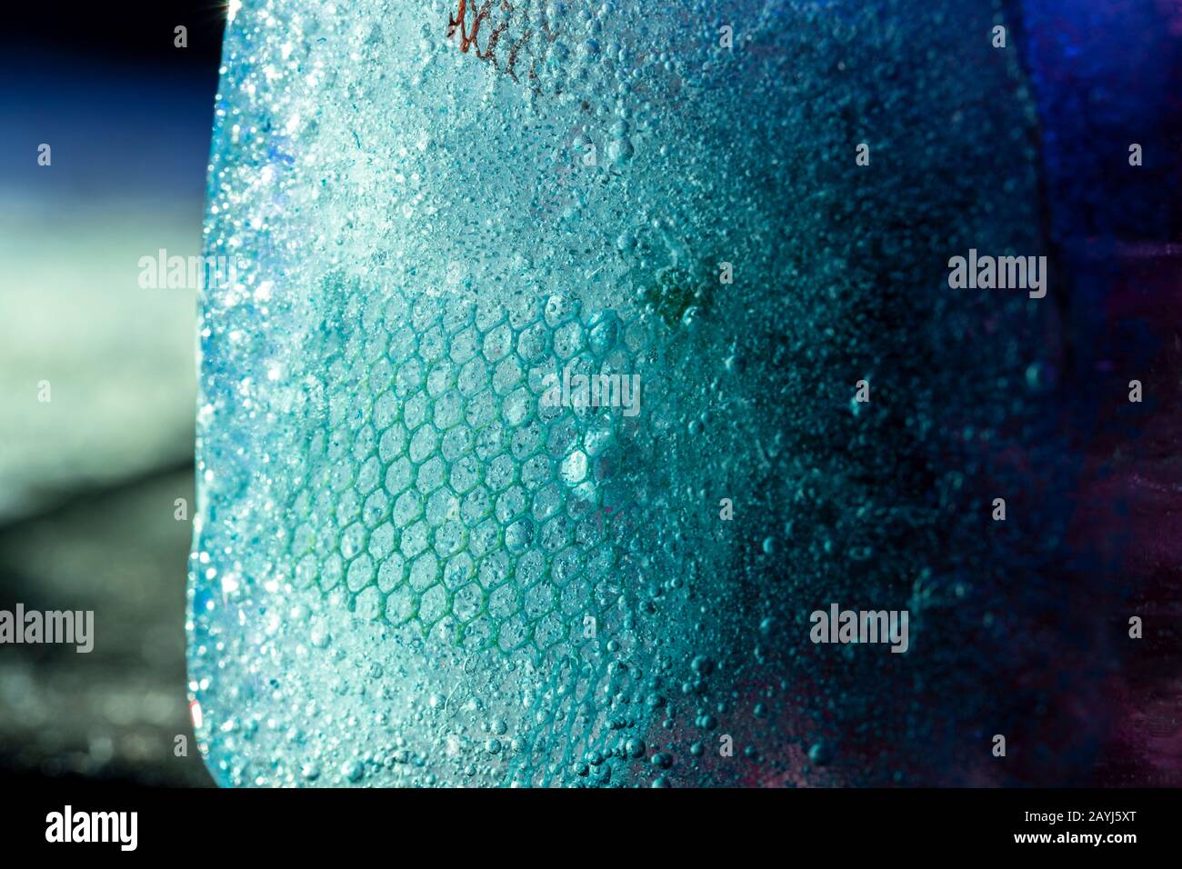 Beleuchteter Eisblock mit tiefgefrorener Textur - moderner abstrakter Makrohintergrund in Blautönen Stockfoto