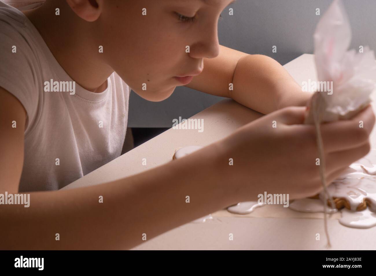 Ein 10-jähriger Junge glasiert Plätzchen mit einer kulinarischen Tüte. Handgefertigt. Kreativität der Kinder Stockfoto