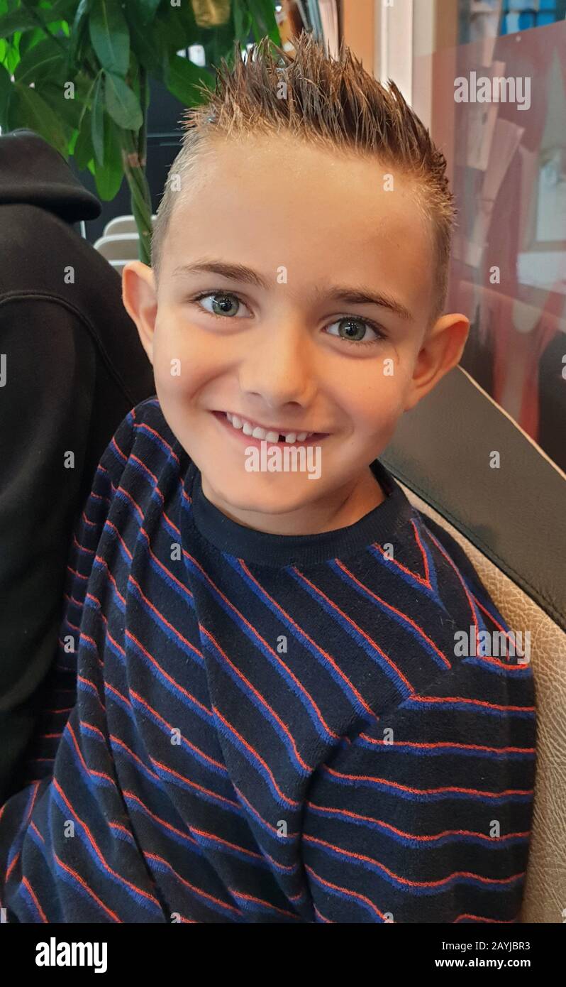 Junge mit frisch gekleideten Haaren und fehlendem Zahn glücklich in die Kamera blicken, Deutschland Stockfoto