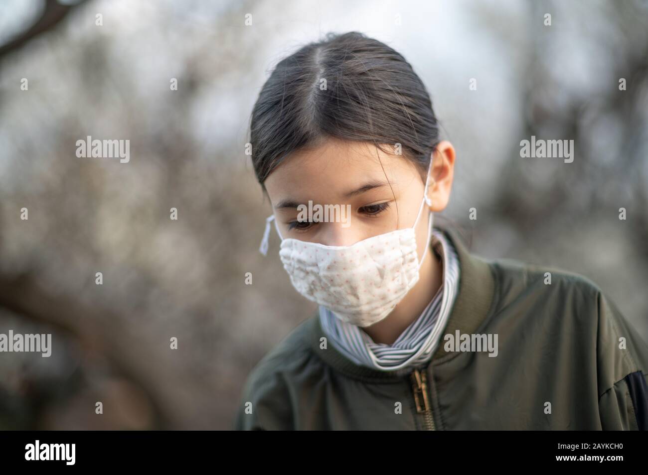 Junges Mädchen / Kind mit gemischter asiatischer - europäischer Ethnie trägt eine Gesichtsmaske, um Viren / Allergien zu vermeiden. Nahaufnahme von Außenaufnahmen während Covid-19. Stockfoto