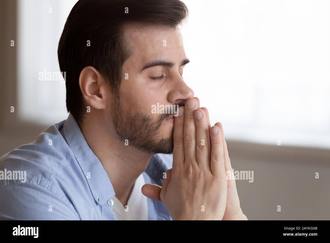 Hoffnungsvoller Mann mit Händen im Gebet bittet um viel Glück Stockfoto