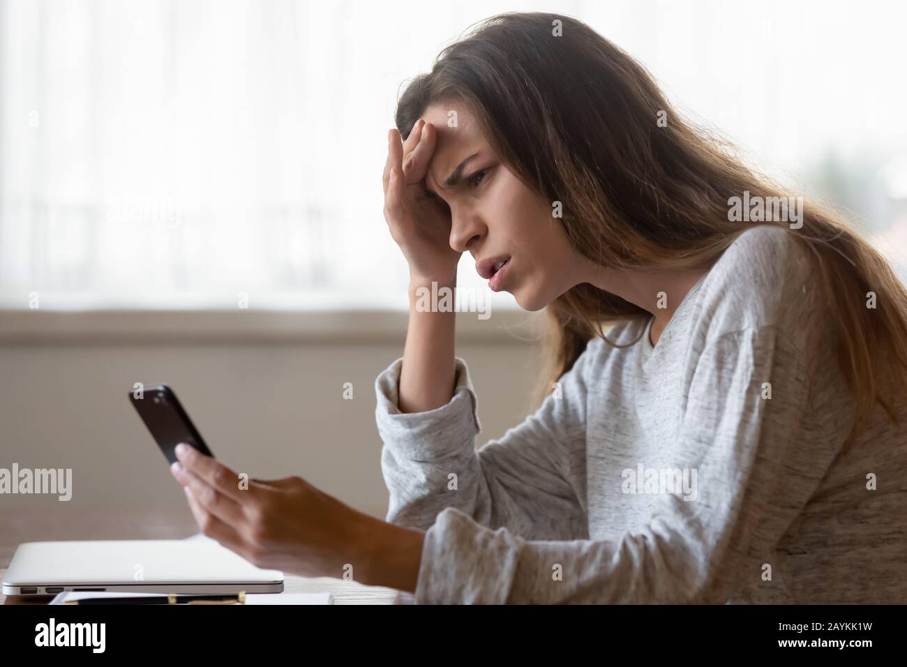 Frustrierte junge Frau fühlt sich wütend, wenn sie Probleme mit dem Smartphone hat Stockfoto