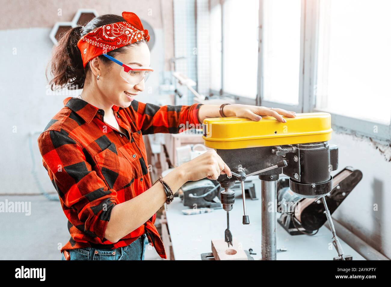 Eine starke und unabhängige Asiatin arbeitet an einer Bohrmaschine in einer Fabrik oder Werkstatt. Konzept mit blauem Kragen Stockfoto