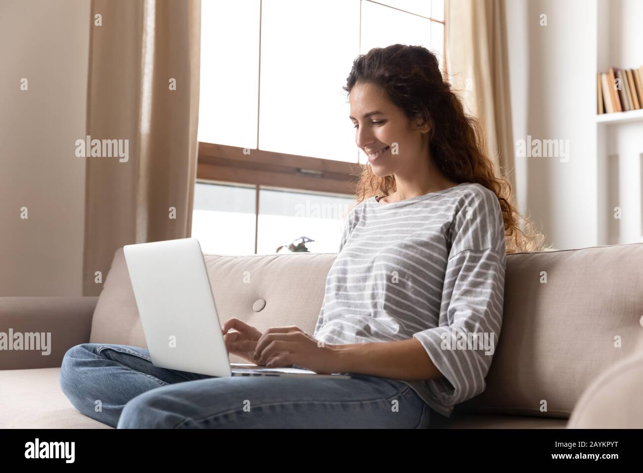 Fröhliche, attraktive junge Frau mit Computer. Stockfoto