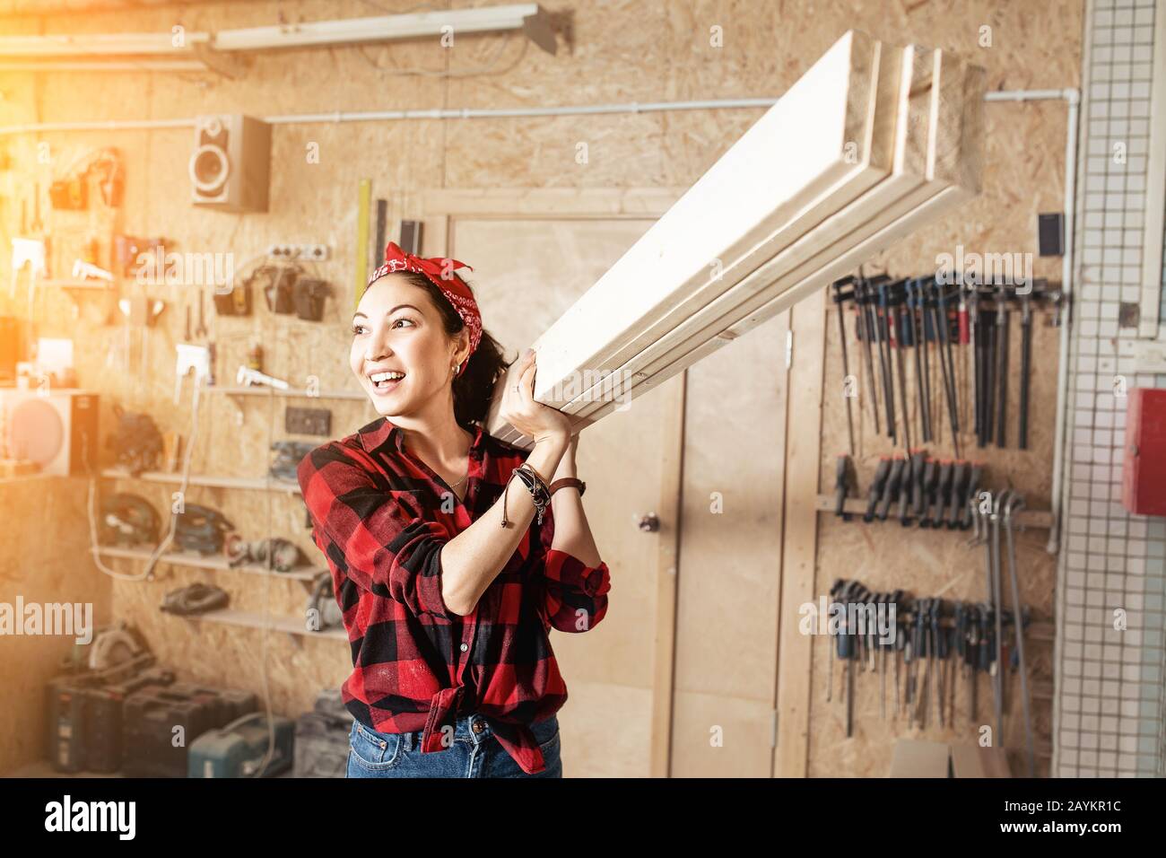 Asian Woman Worker mit Holzbrettern an der Schulter, dem Konzept der Arbeiter mit blauem Kragen und der Reparaturwerkstatt Stockfoto