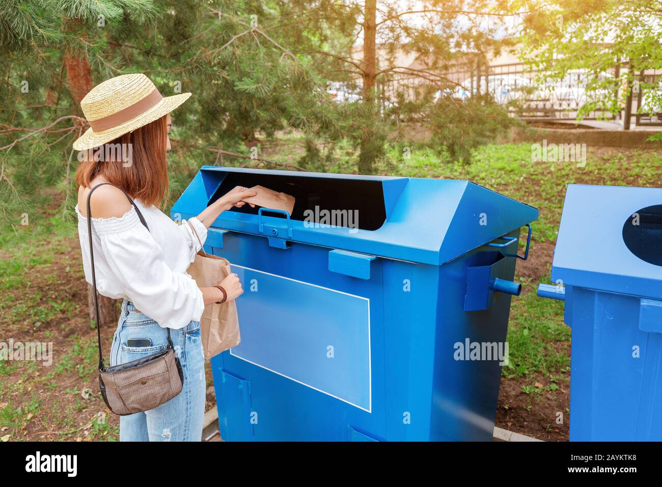 Glückliche asiatin wirft Papier in den Mülleimer. Abfallsortierkonzept Stockfoto