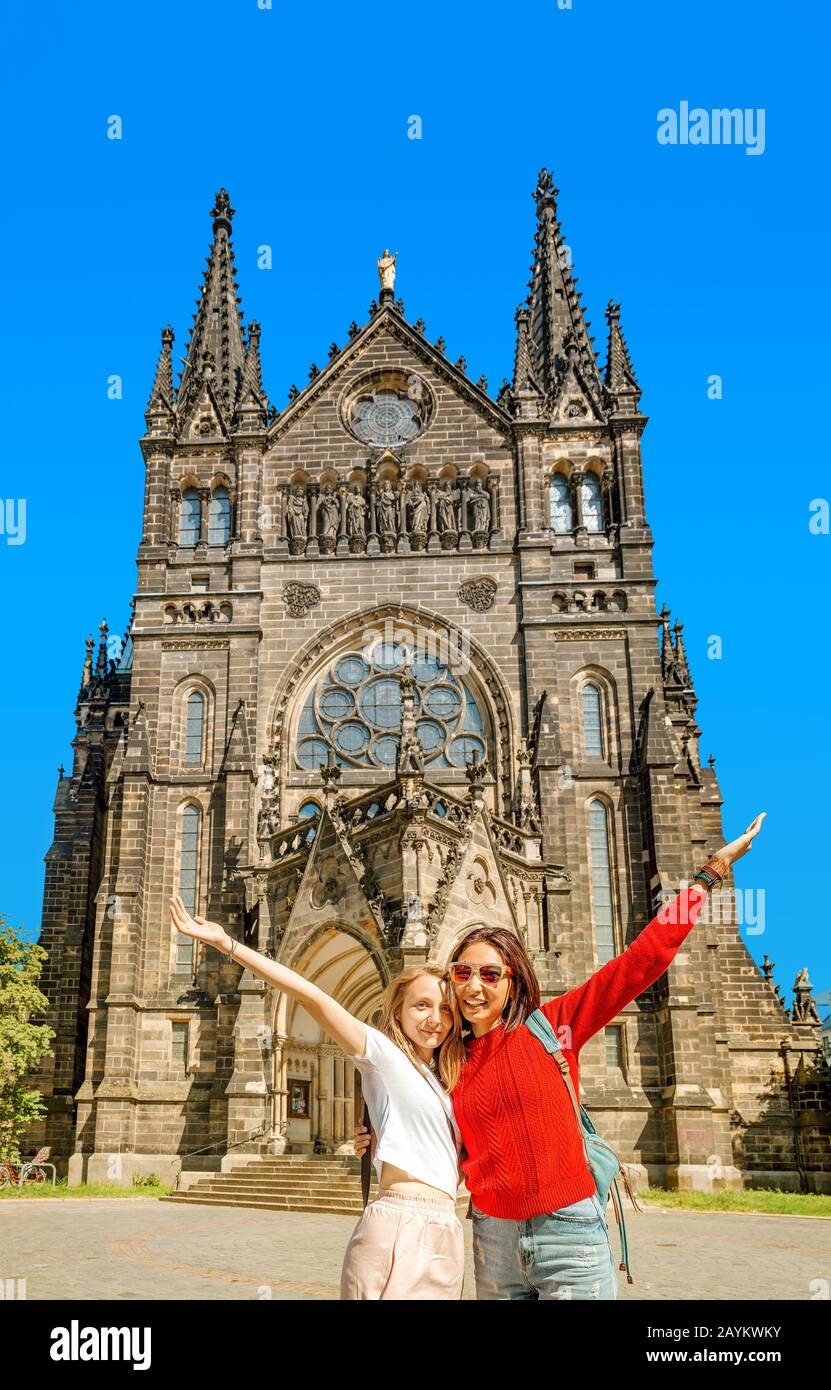 Zwei Mädchentouristen-Freunde umarmen sich vor dem Hintergrund der Peterskirche in Leipzig Stockfoto