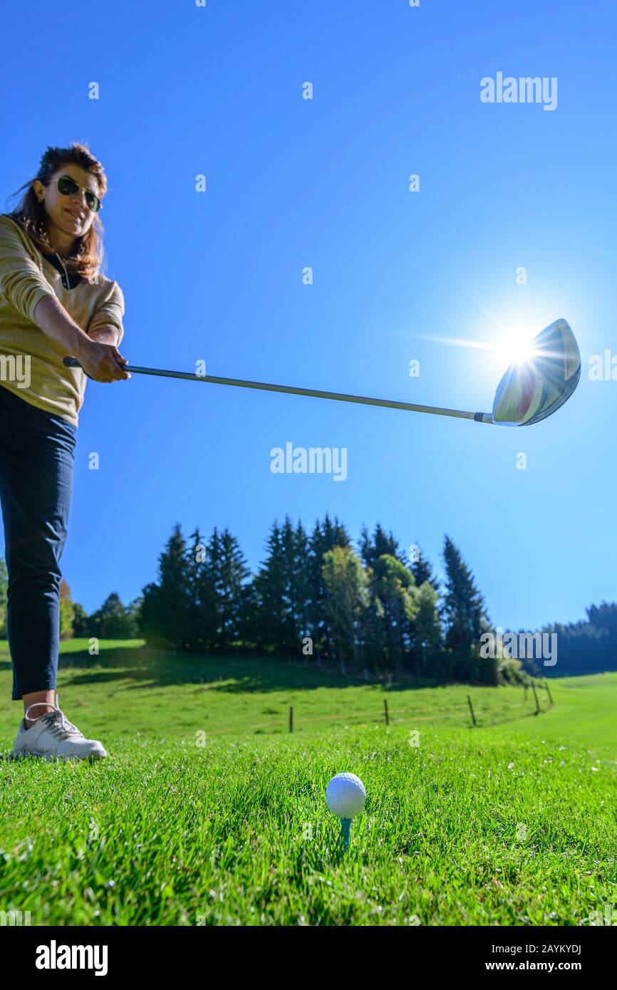 Femaler Golfspieler schlägt mit Fahrer auf einen Ball Stockfoto