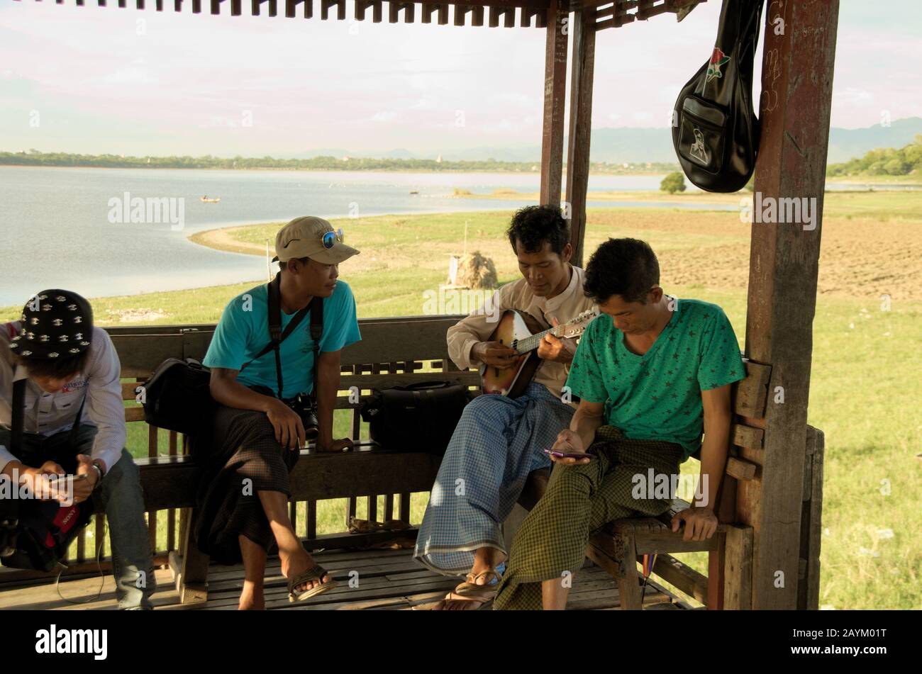 Lokale Birmanesen spielen Musik mit Mandoline auf einer Rasthütte an der U-bein-Brücke. Foto von U-bein Bridge, Amarapura, Mandalay, Myanmar. Stockfoto