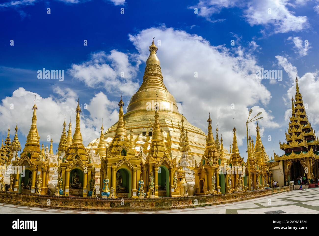 Pagoden umkreisen die Basis des vergoldeten Stupa der Shwedagon-Pagode, Yangon, Myanmar. Einige gebeten und Touristen ruhen unter der braunen Pagode. Stockfoto