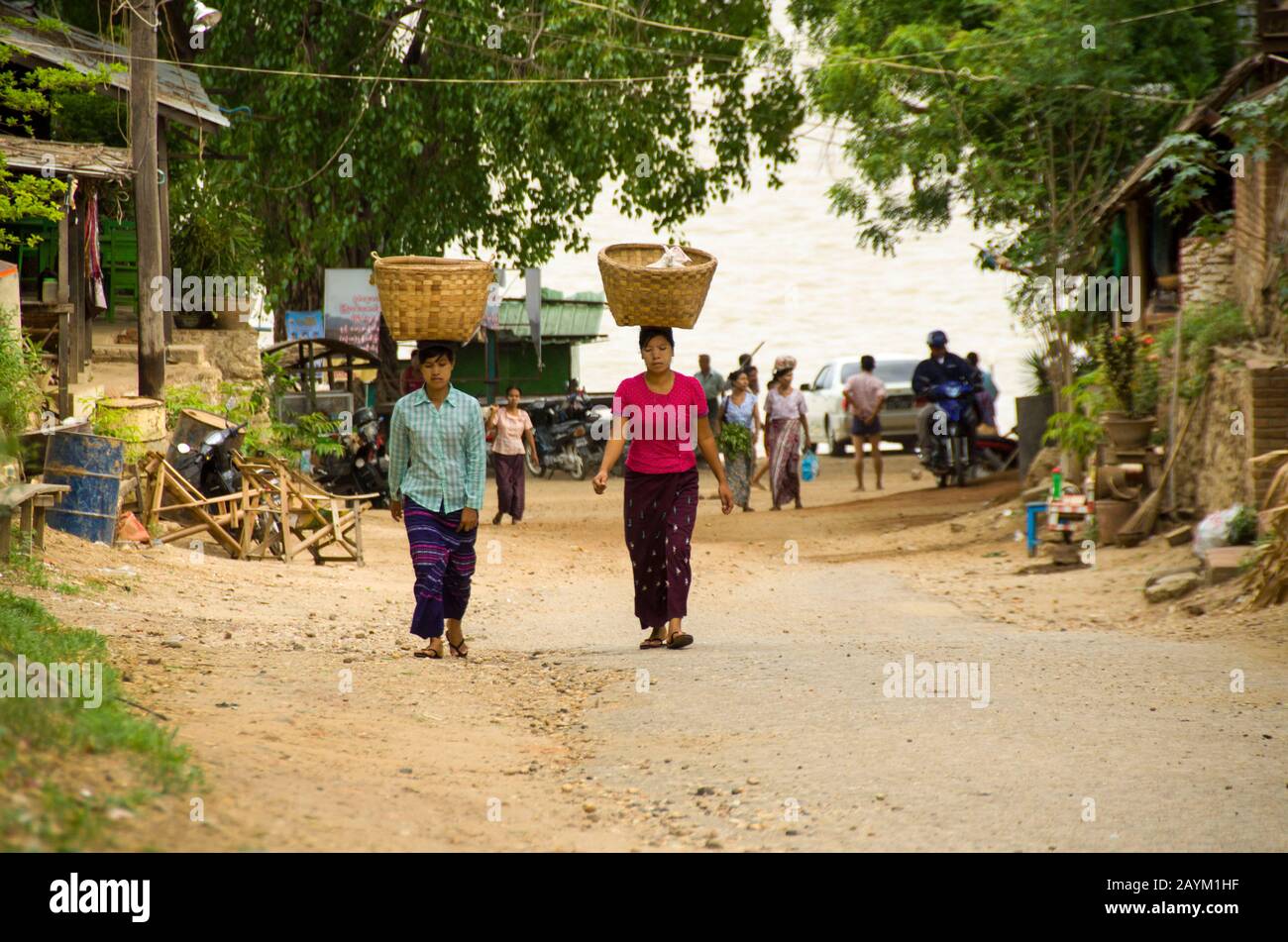 Myanmar-Frauen, die großen Bambuskorb auf dem Kopf tragen und auf der Sandstraße am Strand in Myanmar spazieren gehen Stockfoto