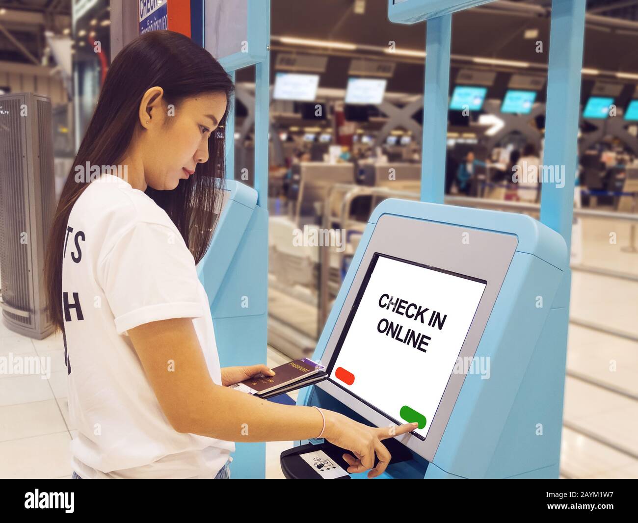 Junge Asianerin mit Reisepass, die einen interaktiven Touchscreen mit Selbstcheck-Kiosk am Flughafen verwendet und einen Selbstcheck für Flug oder den Kauf von Airplas macht Stockfoto