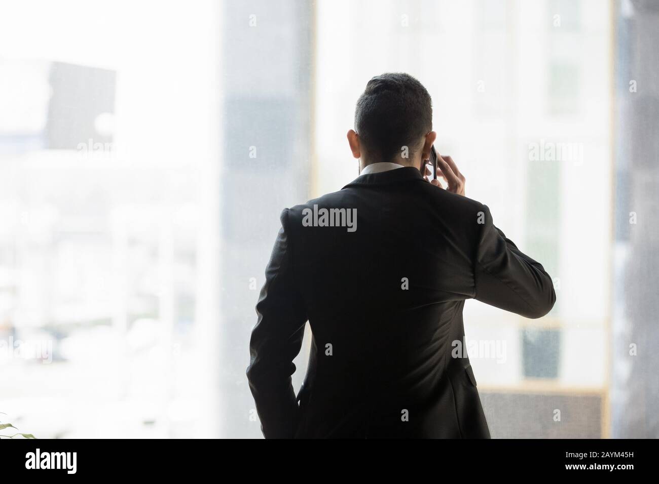 Business mit Blick auf die Rückseite in formeller Anzug Telefonieren im Innenbereich Stockfoto