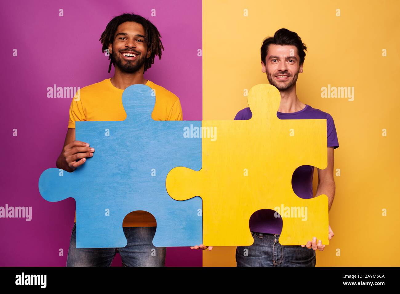 Freunde mit Rätsel in Hand auf gelben Hintergrund. Konzept der Integration, Union und Partnerschaft Stockfoto