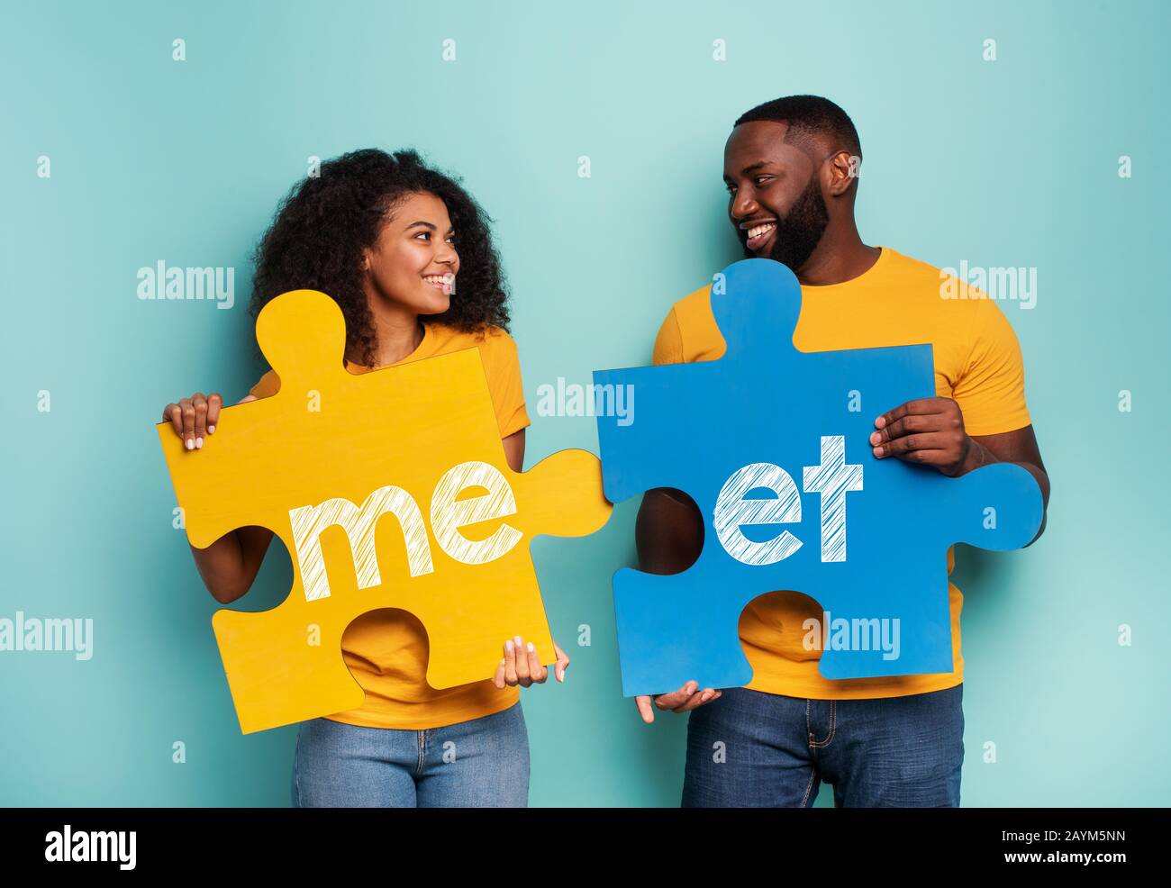 Paar mit Puzzles in Hand über hellblauen Hintergrund. Integrationskonzept, union, Beziehung und Partnerschaft Stockfoto