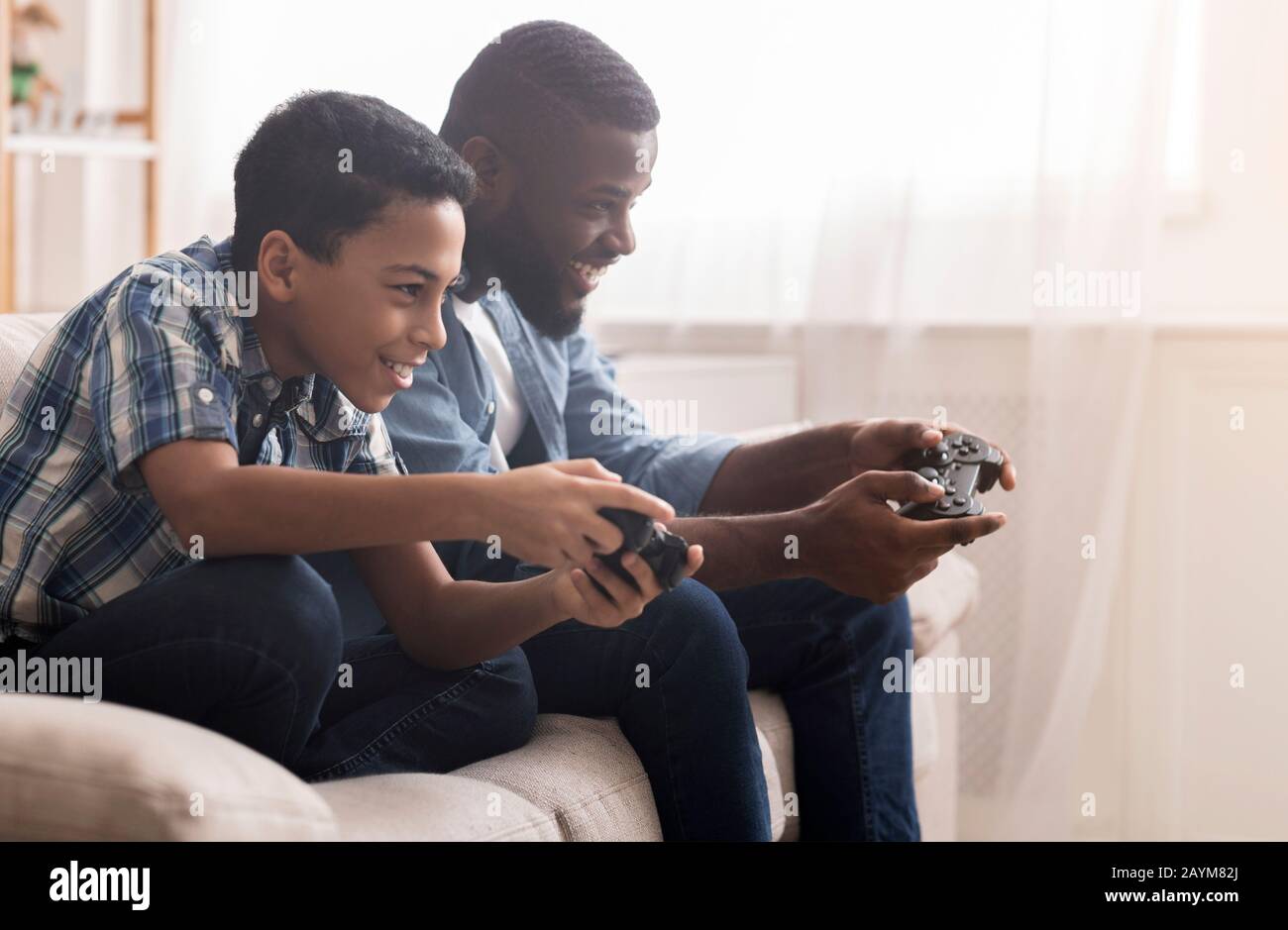 Afro Vater und Sohn spielen Videospiele mit Joysticks Stockfoto